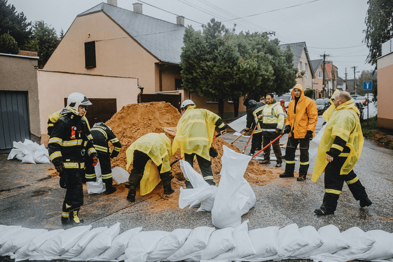Emergency workers fill sandbags on a rain-soaked street to protect nearby properties from flooding.