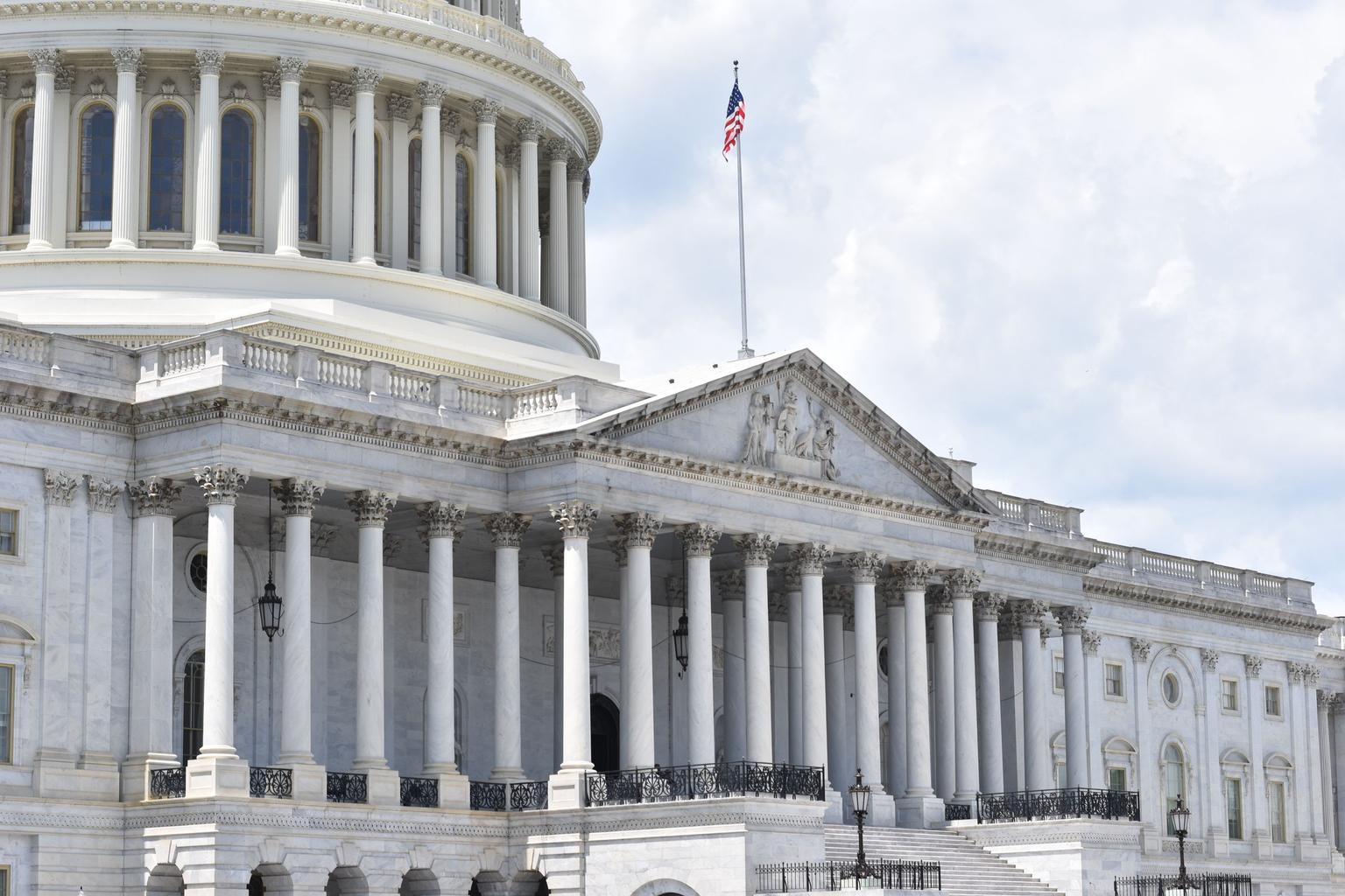 Close exterior view of U.S. Capitol columns and facade with a small American flag.