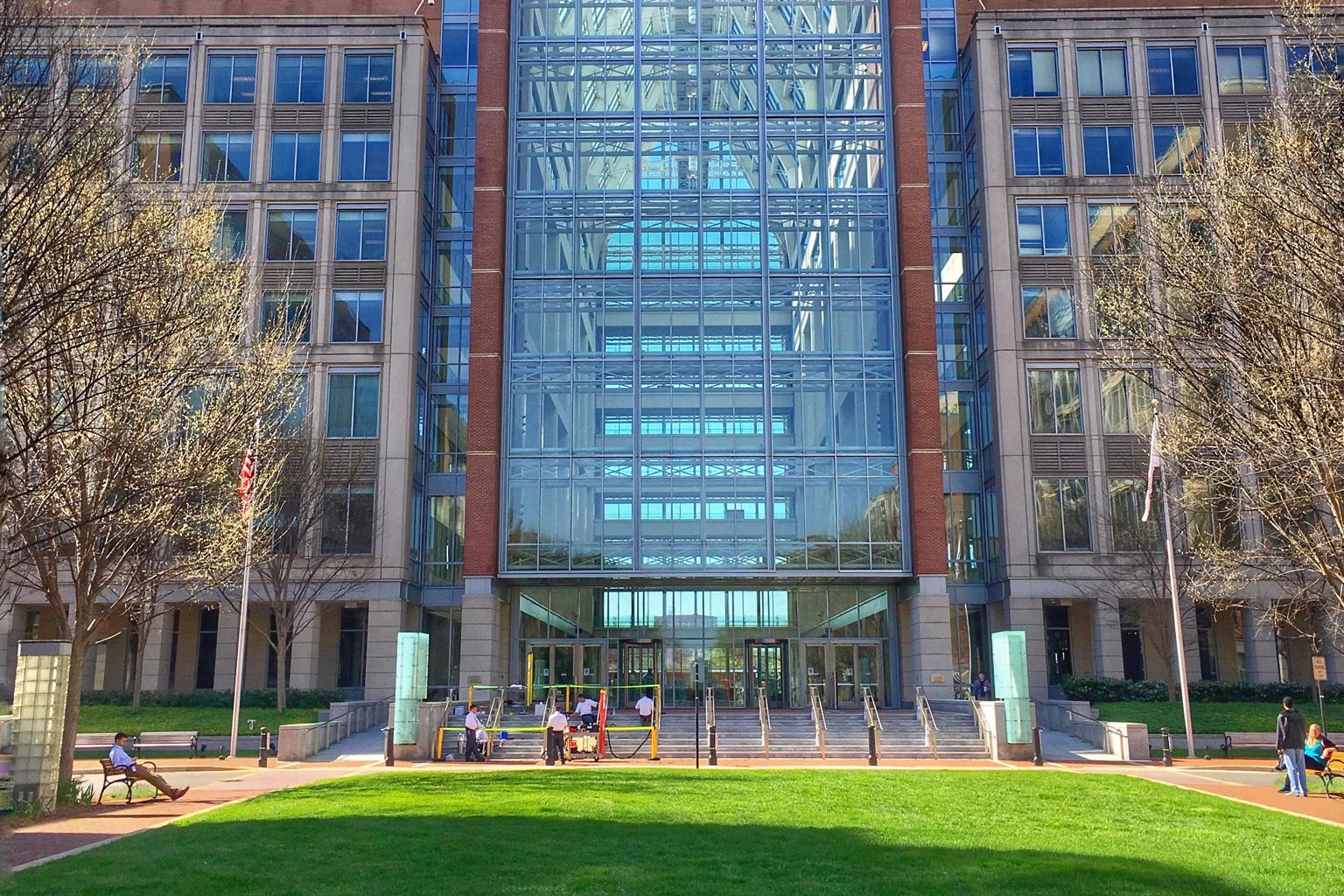 The U.S. Patent and Trademark Office campus in Alexandria, Virginia, has a central glass atrium and small American flags by the entrance.