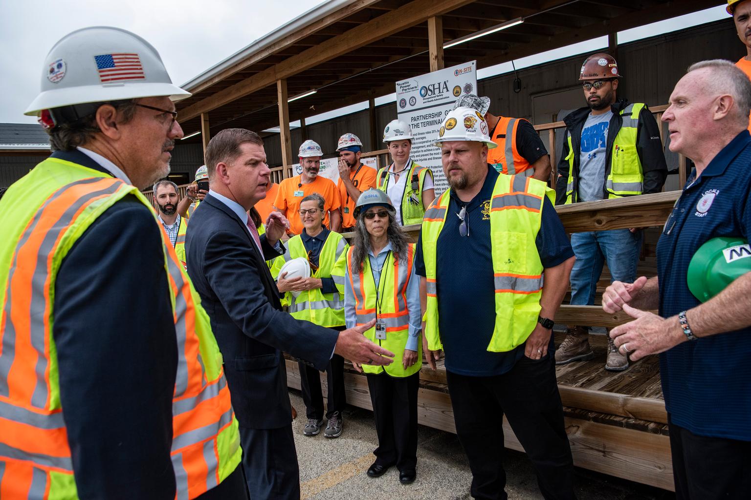 U.S. Labor officials and construction workers at a Chicago worksite with OSHA signage.