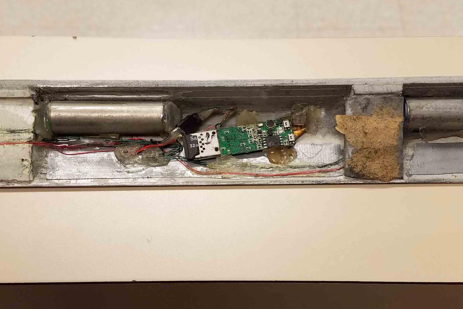Batteries, wiring, a memory card, and camera electronics concealed in an ATM panel recovered in an FBI skimming case.