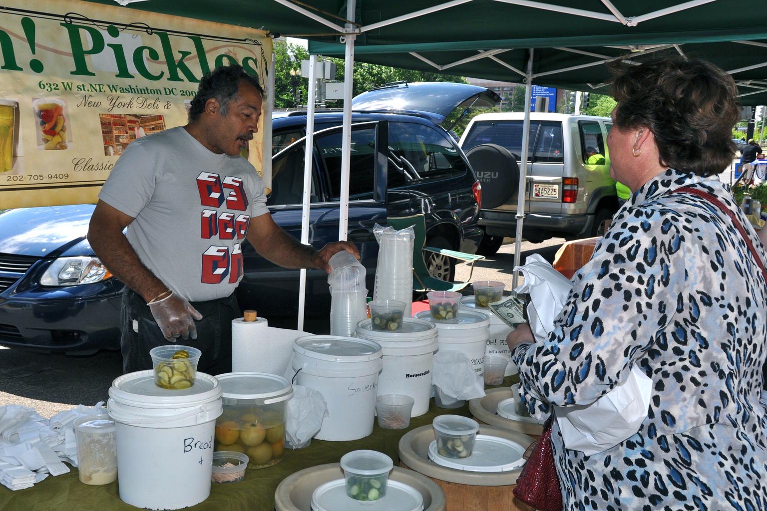 A pickle vendor talks with customers at the USDA Farmers Market in Washington, D.C.