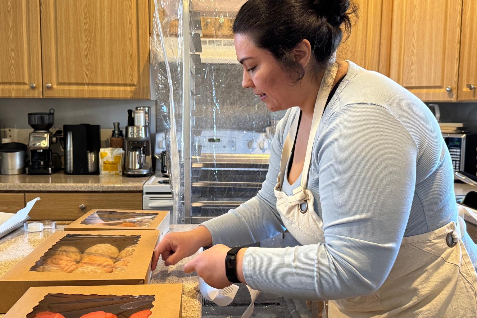 Home-based baker Lupe Najarro labels boxes of baked goods in her kitchen in Tacoma, Washington.