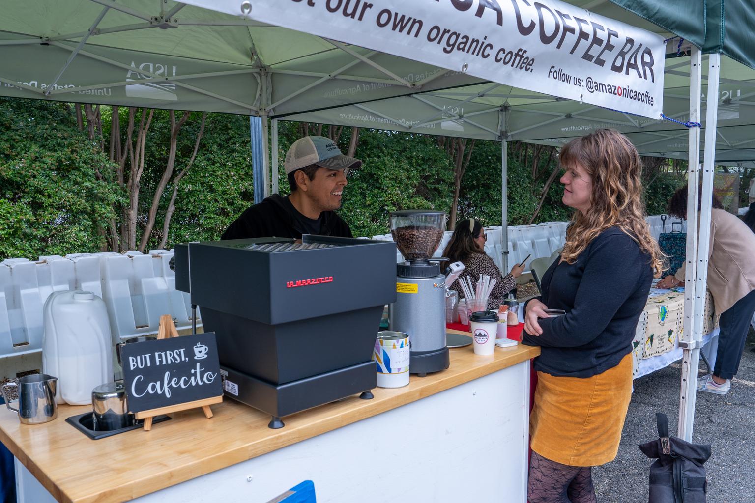 A coffee vendor speaks with a customer at the USDA Farmers Market on the National Mall in Washington, D.C.